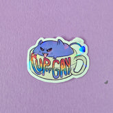Holographic sticker with a gremlin in a cup with rainbow text reading 'Cup of Gay'