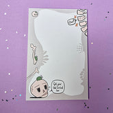 Memo pad with decorative border showing various skeleton and skulls. Top right has a spine that is cracking with 'Ow!' speech bubble coming from it. Bottom left has a skull with a small frog on it. Skull has speech buble saying 'Get your shit sorted luv,'
